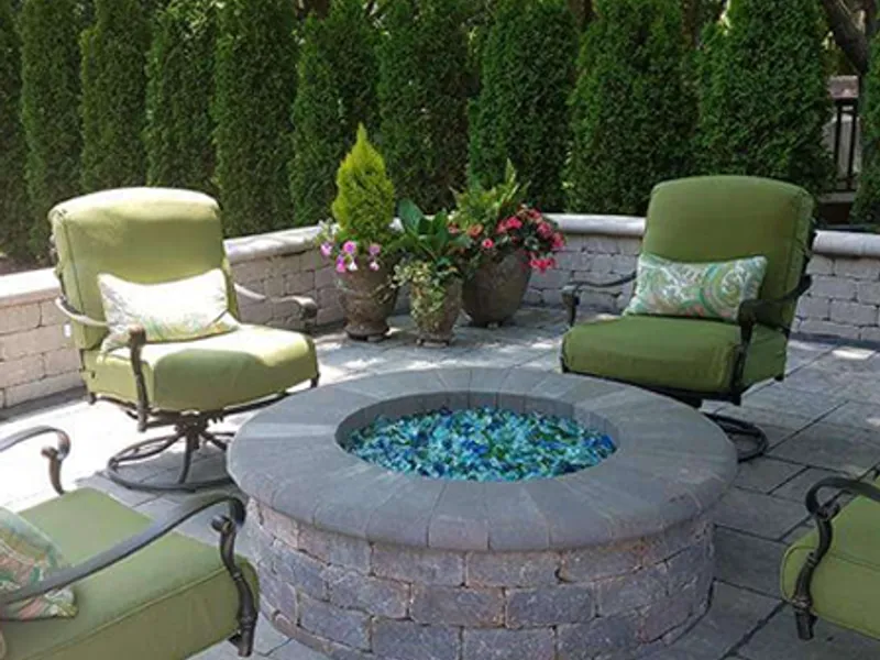 Paver patio with cushioned outdoor seating and potted evergreens