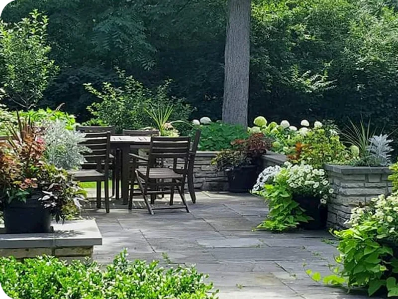Bluestone patio with a dining set framed by garden beds